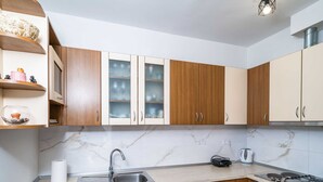 Una cocina moderna con armarios de madera, encimera de mármol, lavavajillas, fregadero, estufa y hervidor.
