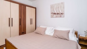 Un dormitorio con cama, armario de madera y un cuadro de veleros en la pared.