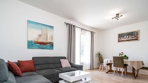 Una sala de estar moderna con un sofá gris, una mesa de centro blanca y un comedor con mesa y sillas.