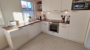 Una cocina moderna con armarios blancos, horno de acero inoxidable, microondas y ventana con vistas.