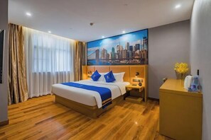 A hotel room with a large bed, a cityscape painting on the wall, a wooden floor, and a desk with a vase of flowers. - Super 8 Hotel Select (Guangzhou Station Xicun Metro Station) (Guangzhou)