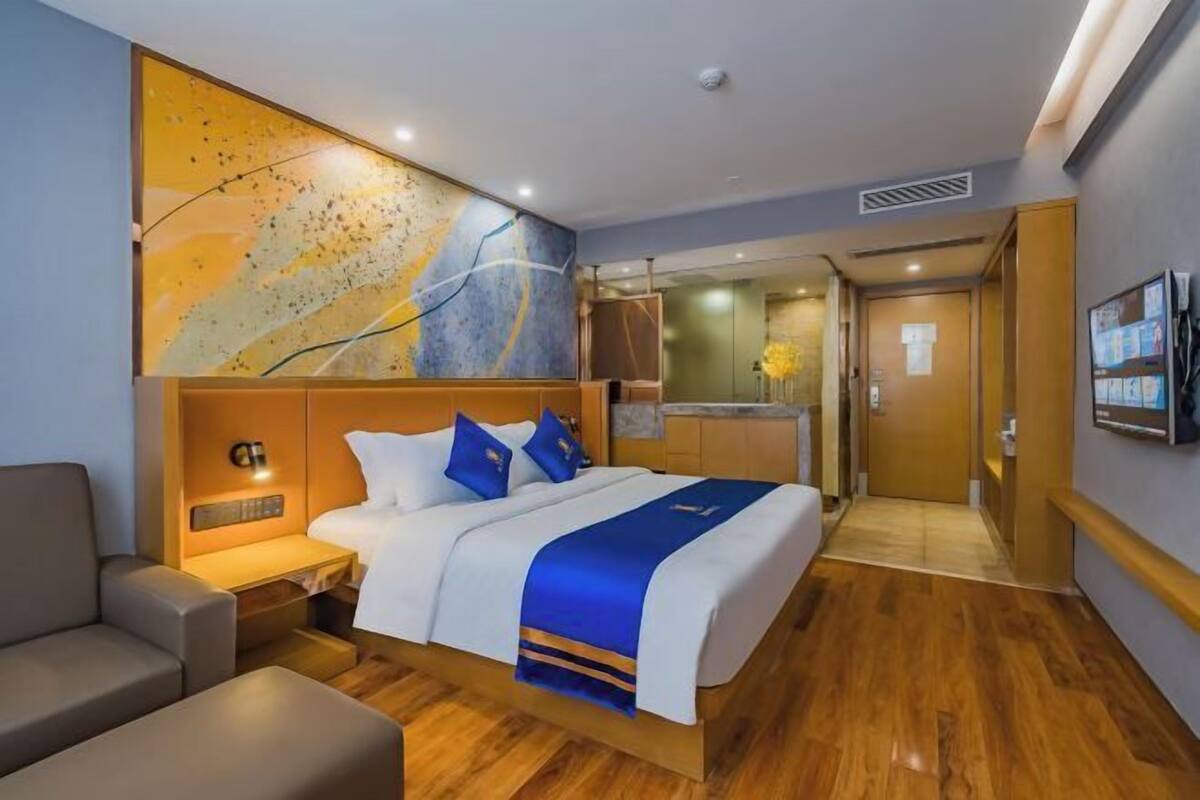 A hotel room with a bed, bedside table, and a large abstract painting on the wall.