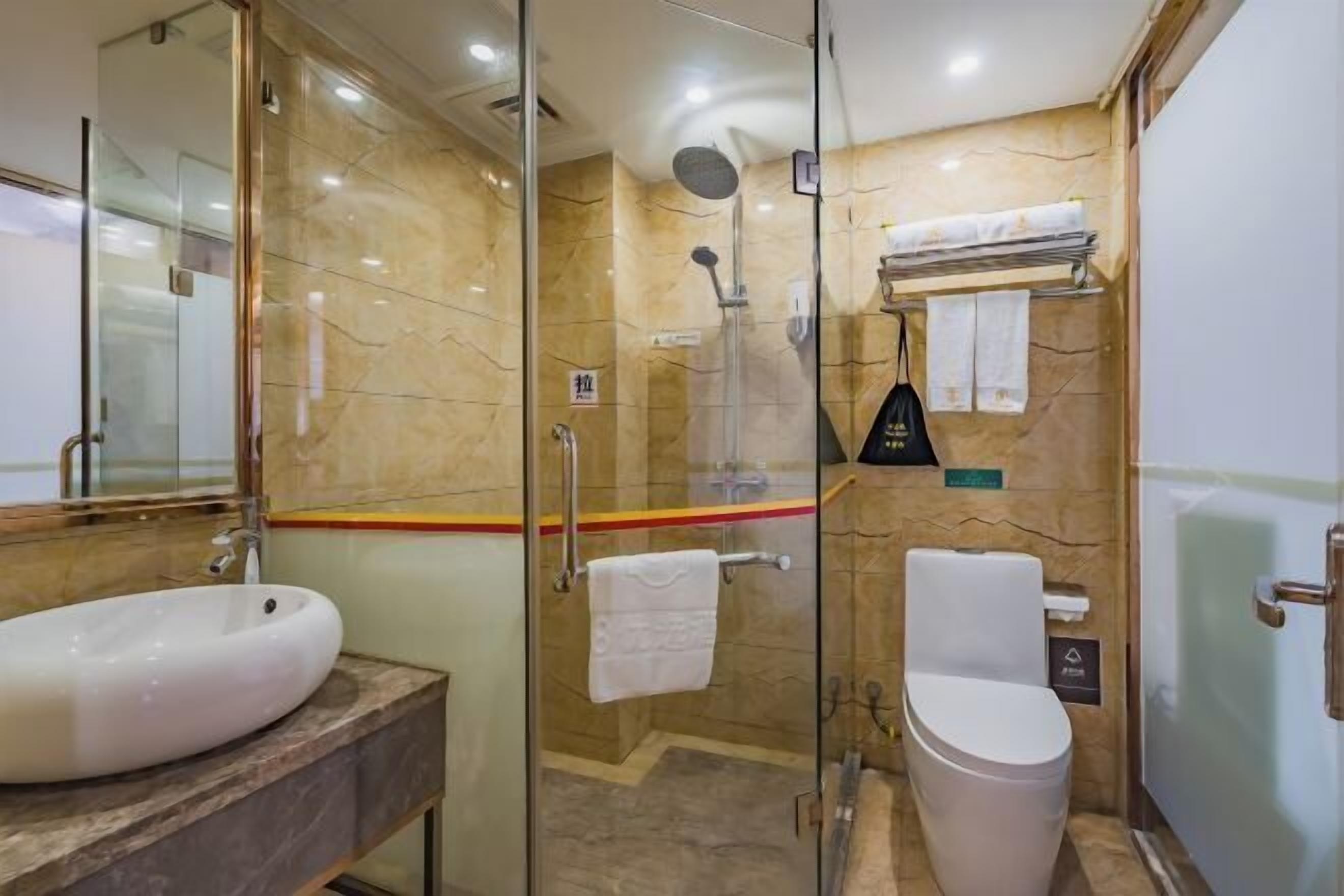 Une salle de bain avec une douche à parois de verre, un lavabo blanc et des toilettes.