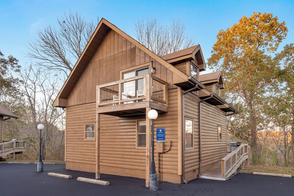 Een houten hut met een balkon, een overdekte veranda en een klein terras.