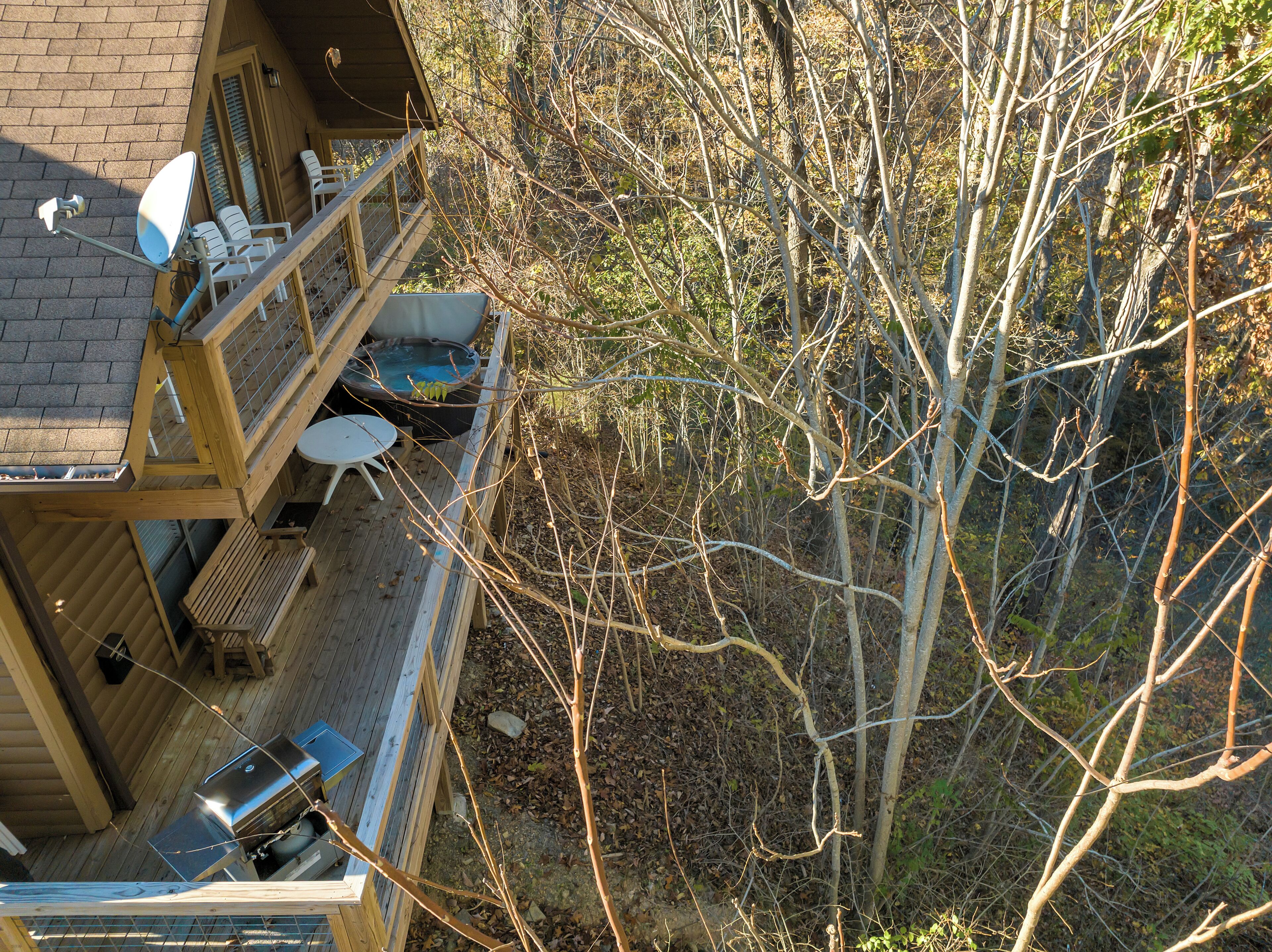 A wooden deck with a hot tub, barbecue grill, and outdoor seating.