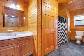 Een houten badkamer met een wastafel, spiegel en toilet.