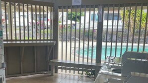 Un espace extérieur abrité comprenant une piscine, des bancs et des toilettes.