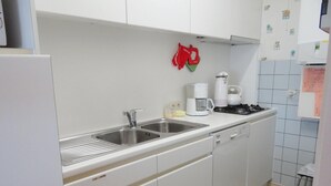 Una cocina compacta con lavabo, estufa y cafetera.