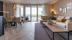 A modern hotel room with a dining area, a sofa set, a large window with a view, and a balcony. - Loft Apartment by Veerse Meer Marina (Kamperland)