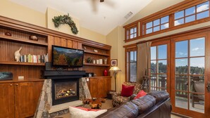 A cozy living room with a fireplace, comfortable seating, and a large window offering a scenic view. - Ultimate ski-in, ski-out!  Steps from ski lifts & gondola. Resort amenities! Air Conditioning! (Breckenridge)