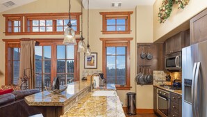 A kitchen with a large island, wooden cabinets, stainless steel appliances, and large windows offering a view of the mountains. - Ultimate ski-in, ski-out!  Steps from ski lifts & gondola. Resort amenities! Air Conditioning! (Breckenridge)