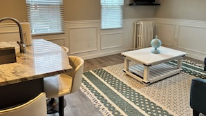 A modern kitchen with a marble countertop, a sink, and a chair. There is a patterned rug on the floor and a television mounted on the wall. - 2 Bedroom Rental in Newport w/ Parking! Steps away from Thames, Broadway, & DT! (Newport)