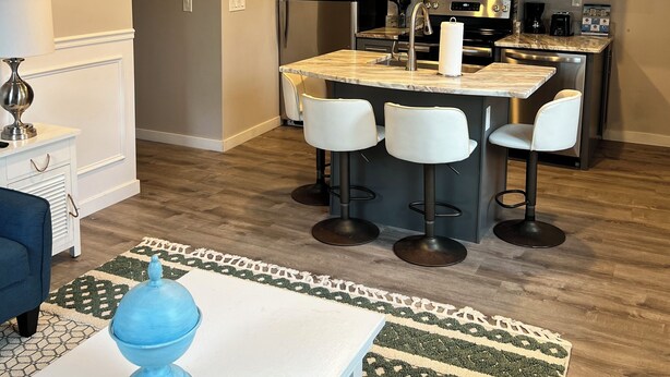A modern kitchen with a central island, bar stools, and a dining area with a table and chairs. - 2 Bedroom Rental in Newport w/ Parking! Steps away from Thames, Broadway, & DT! (Newport)