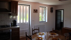 Una cucina con tavolo da pranzo per quattro persone, piano cottura e pensili.