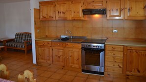 A kitchen with wooden cabinets, a stainless steel stove, and a red pendant light. - Belvilla by OYO Negritella Quadri Sette (Cavalese)