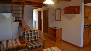 A cozy interior with a wooden ceiling, a kitchen area with wooden cabinets, a dining area with plaid chairs, and a refrigerator. - Belvilla by OYO Negritella Quadri Sette (Cavalese)