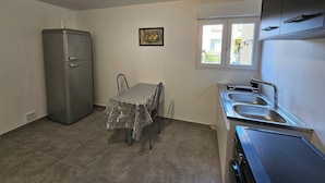 A compact kitchen with a refrigerator, a dining table with chairs, a window with a view, and a sink. - Belle Maison Avec Jardin et Parking Gratuit -10% Séjour 7 j (Carcassonne)