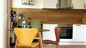 Una cucina moderna con mobili bianchi, un piano di lavoro in legno e un'area pranzo con sedie gialle.