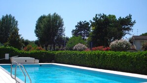 Une piscine rectangulaire avec un escalier en métal sur un côté, entourée d’une terrasse carrelée.