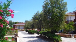 Un quartier résidentiel avec une allée en gravier, des murs en briques et de la verdure.