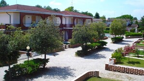 Un quartier résidentiel composé d’une rangée de maisons, avec une cour intérieure agrémentée d’arbres et d’un chemin de gravier.