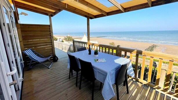 A wooden deck with a table and chairs, overlooking a beach. - Seaside Comfort With Parking (Nieuwpoort)
