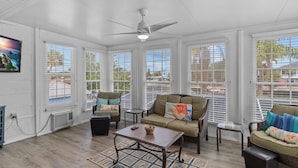 A sunroom with a ceiling fan, large windows, a sofa, a coffee table, and a view of the outside. - HEATED POOL screened in - PET - TIKI - 4 Kayaks - Private Fishing & Boating Dock (Hernando Beach)