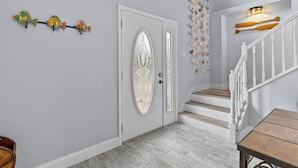 A hallway with a white door, a staircase with white railings, and a wall decorated with fish and seashells. - HEATED POOL screened in - PET - TIKI - 4 Kayaks - Private Fishing & Boating Dock (Hernando Beach)
