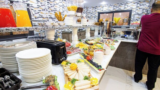 A buffet setup with various food items and utensils. - Beirut Hotel Two (Amman)