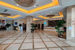 A spacious lobby with a tiled floor, a reception desk, and several potted plants. - Vienna Classic Hotel (Shanghai)