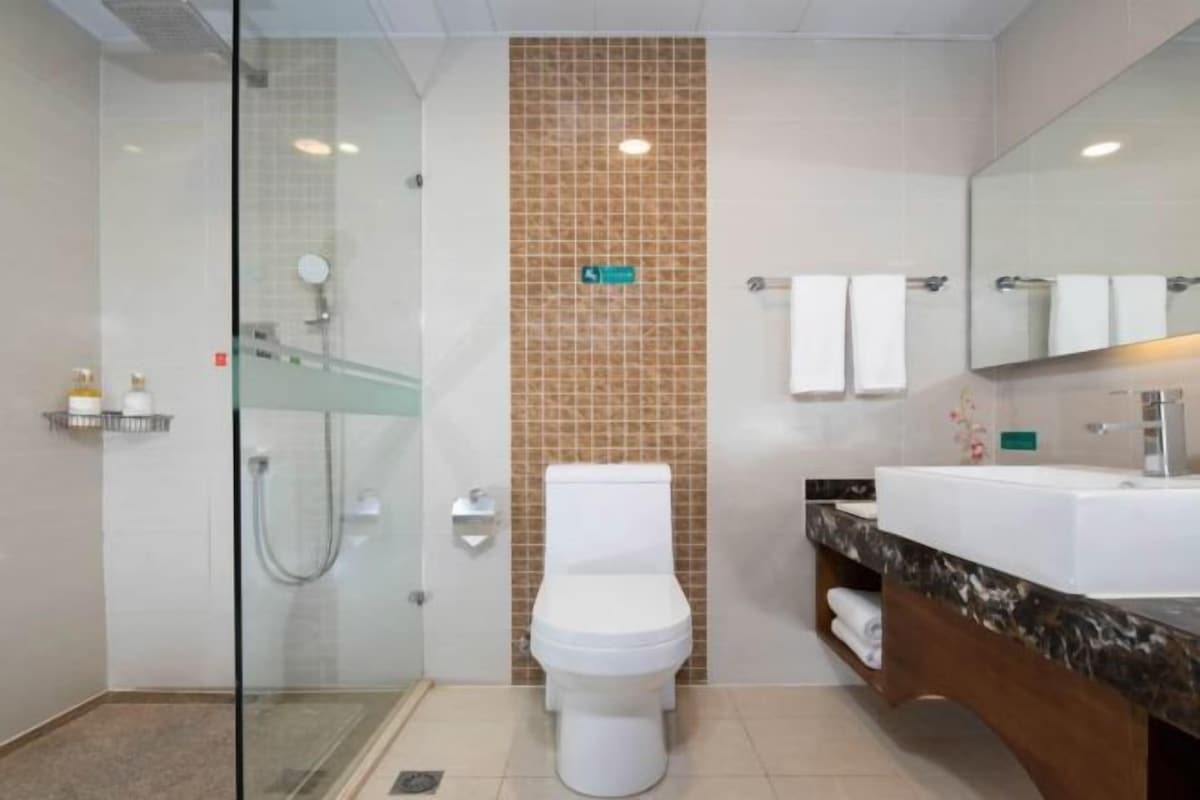 A modern bathroom with a glass-enclosed shower, a white toilet, a vanity with a marble countertop, and a large mirror.