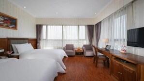A hotel room with two beds, a desk, a chair, a TV, and a window with curtains. - Vienna Classic Hotel (Shanghai)
