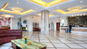 A spacious lobby with a reception desk, seating area, and a large column. - Vienna Classic Hotel (Shanghai)