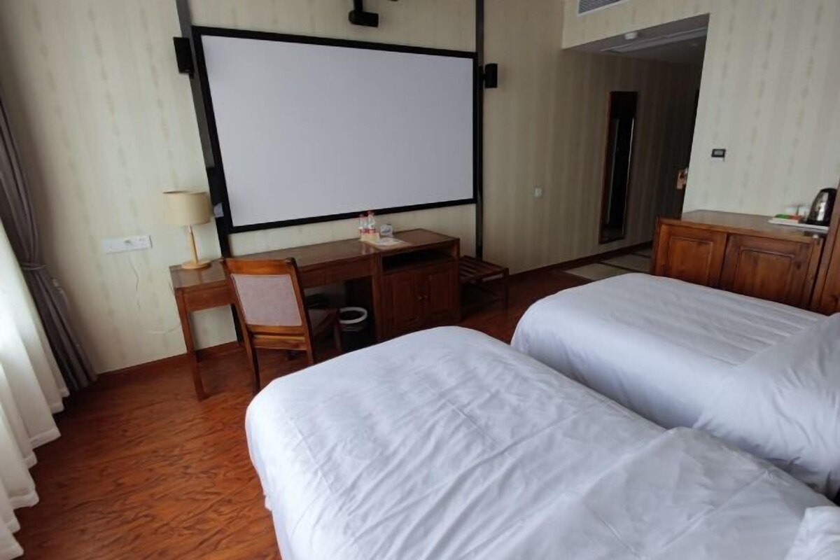A hotel room with a bed, a desk, a chair, a TV screen, and a wardrobe.