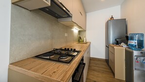 A compact kitchen with a wooden countertop, a gas stove, a built-in oven, a refrigerator, and a water dispenser.