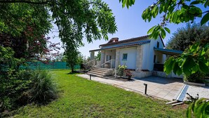 A house with a stone facade, a tiled roof, and a small front yard with steps leading to the entrance.