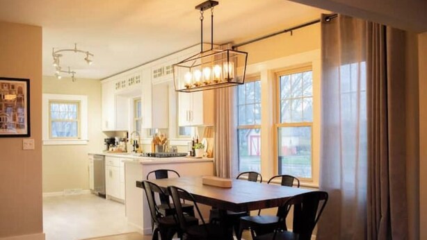 A modern kitchen with white cabinets, a central island, and a dining area with a wooden table and chairs.