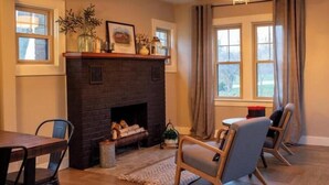 A cozy living room with a fireplace, a dining table, and comfortable seating.