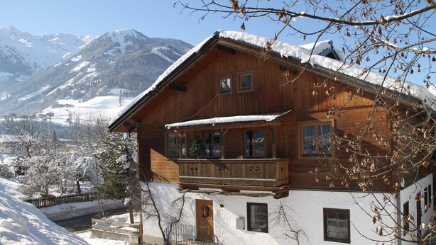A wooden chalet with a balcony, a snow-covered roof, and a view of mountains in the background. - Flat in Mittersill Near Ski Slopes (Mittersill)