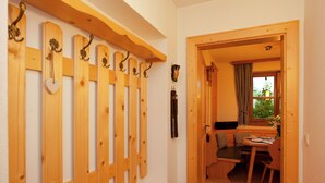 A wooden wall with hooks and a bench, leading to a dining area with a table and chairs. - Flat in Mittersill Near Ski Slopes (Mittersill)