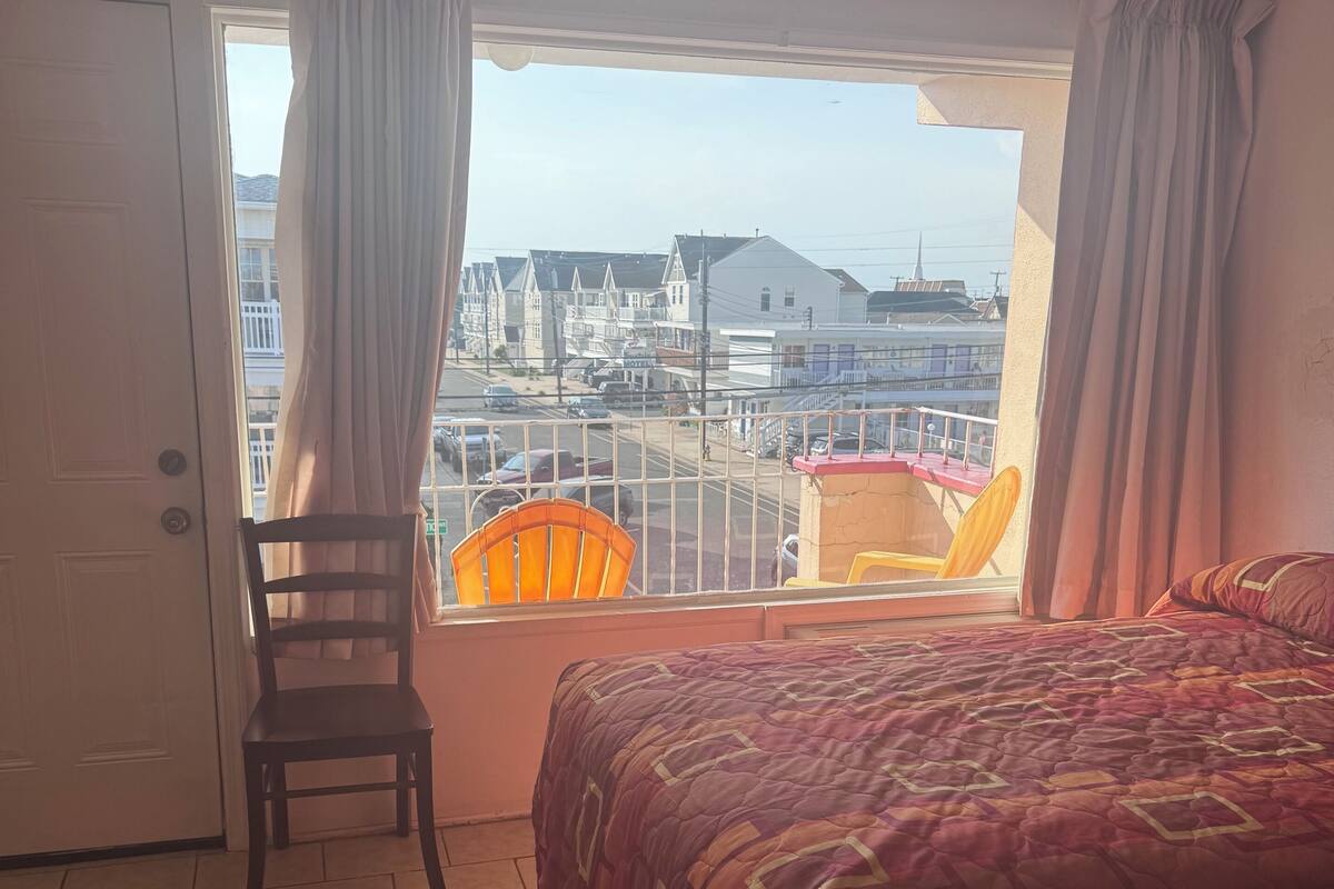 A bedroom with a bed, a chair, and a window with curtains.