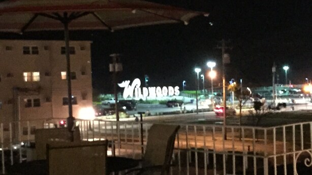 An outdoor seating area with a view of a building with illuminated signage. - El Ray motel (Wildwood)