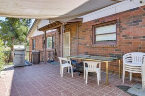 Een terras met een tafel, stoelen, een barbecue en een vuilnisbak.