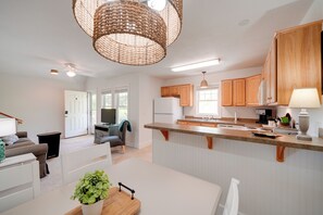 A modern kitchen with wooden cabinets, a white countertop, and a hanging light fixture. - Buxton Vacation Rental w/ Shared Canal Access! (Buxton)