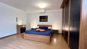 A bedroom with a wooden bed, a nightstand, a dresser, and a wardrobe. - La Piazzetta Verde - Affitti Brevi Italia (Lecco)