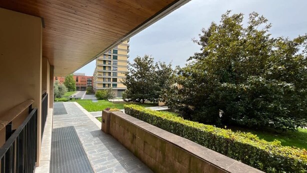 A balcony with a view of a landscaped garden and a building in the background. - La Piazzetta Verde - Affitti Brevi Italia (Lecco)