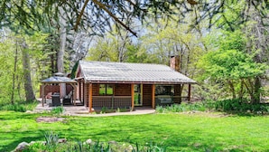 Une cabane rustique avec une façade en bois, une véranda et une petite dépendance attenante.