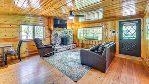Un intérieur de chalet chaleureux avec des murs en bois, une cheminée en pierre, des sièges en cuir et de grandes fenêtres.