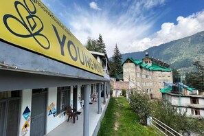 Ostello con un cartello giallo che riporta "YOUNGHOSTEL.COM" e vista su un paesaggio montuoso sullo sfondo.