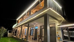 A two-story building with a balcony and a covered outdoor area. - Young Monk Hostel & Cafe Old Manali (Manali)
